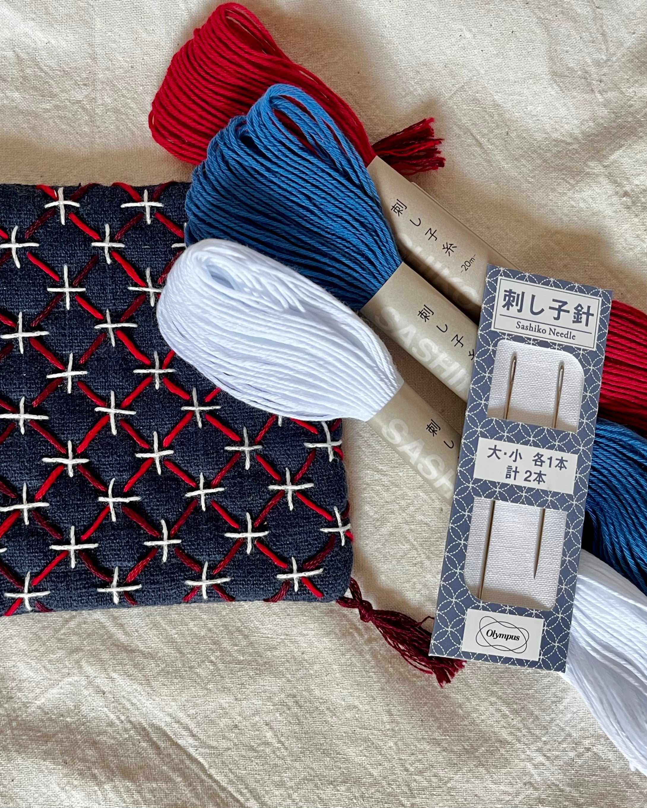 Hand-woven pouch with red, white, and blue pattern on a textured fabric background